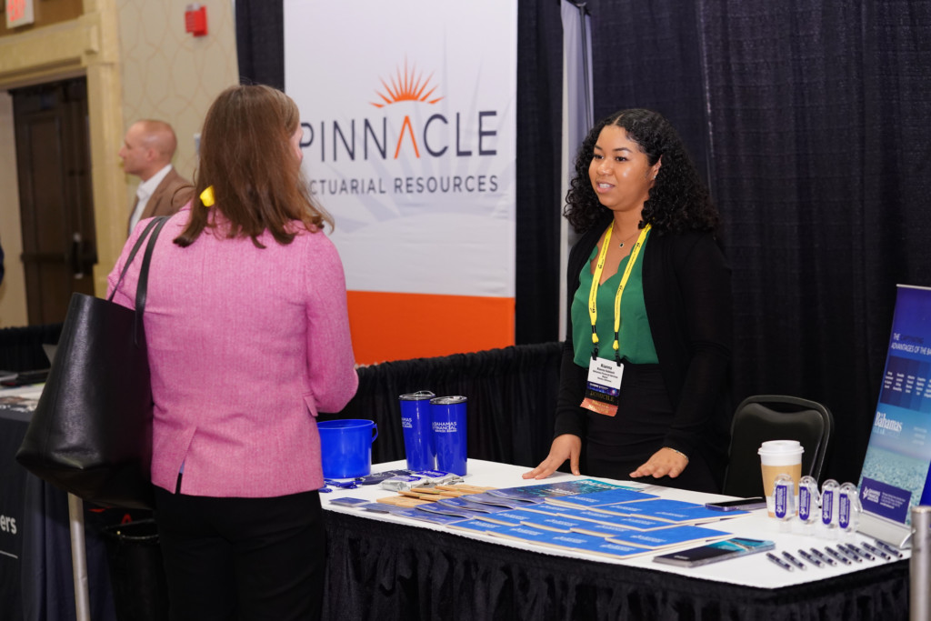 CICA 2023 International Conference exhibitor speaks to attendee at the Bahamas booth